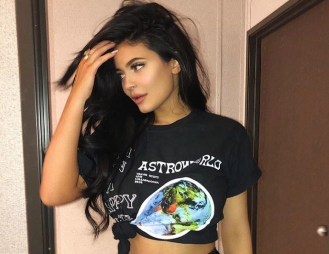 Kylie sits in a manger and cuddles a lamb in Travis Scott’s music video
